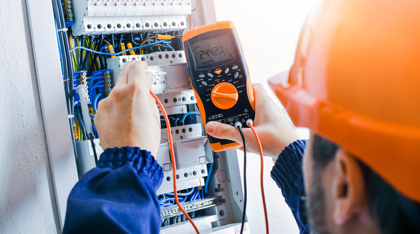 Électricien professionnel effectuant des tests de vérification sur un panneau électrique moderne dans une résidence québécoise